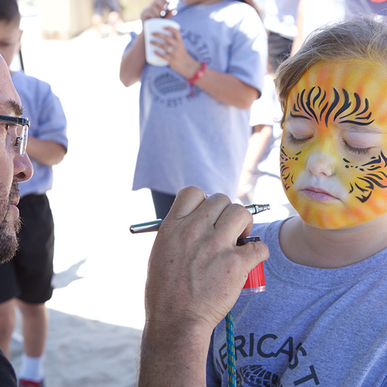 Girl in Branded Swag at Face Paint Station During Auto Part Company Picnic in Los Angeles