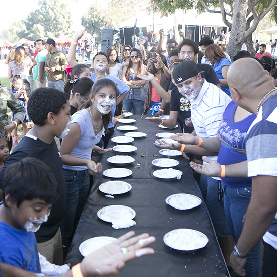 Group During Pie Eating Contest Picnic Game at Altamed's Halloween Picnic in Los Angeles