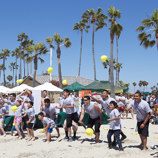 Group Playing Water Balloon Toss Field Game at Auto Part Company Picnic in Los Angeles