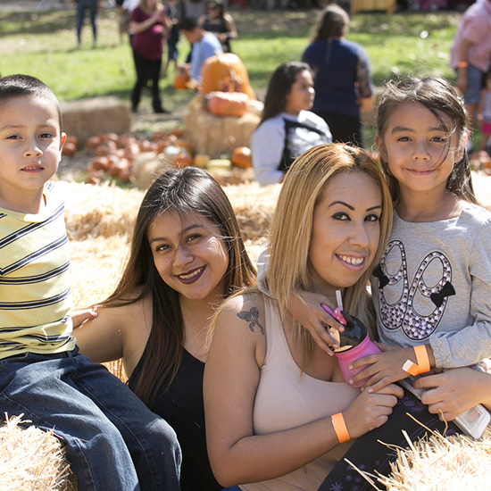 Group Posing with Pumpkins and Hay Bales Picnic Decor at Altamed's Halloween Picnic in Los Angeles