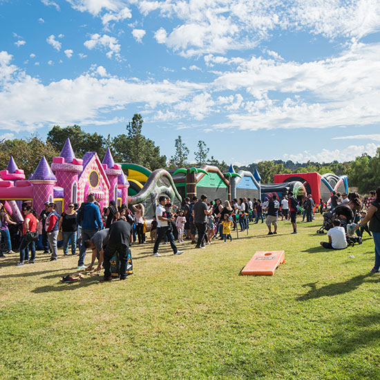 Crowd Enjoying Picnic Inflatables and Corn Hole Field Game at AltaMed Día de Muertos Picnic in Los Angeles