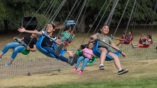 Group Enjoying Swing Carnival Ride Picnic Entertainment at AltaMed Día de Muertos Picnic in Los Angeles
